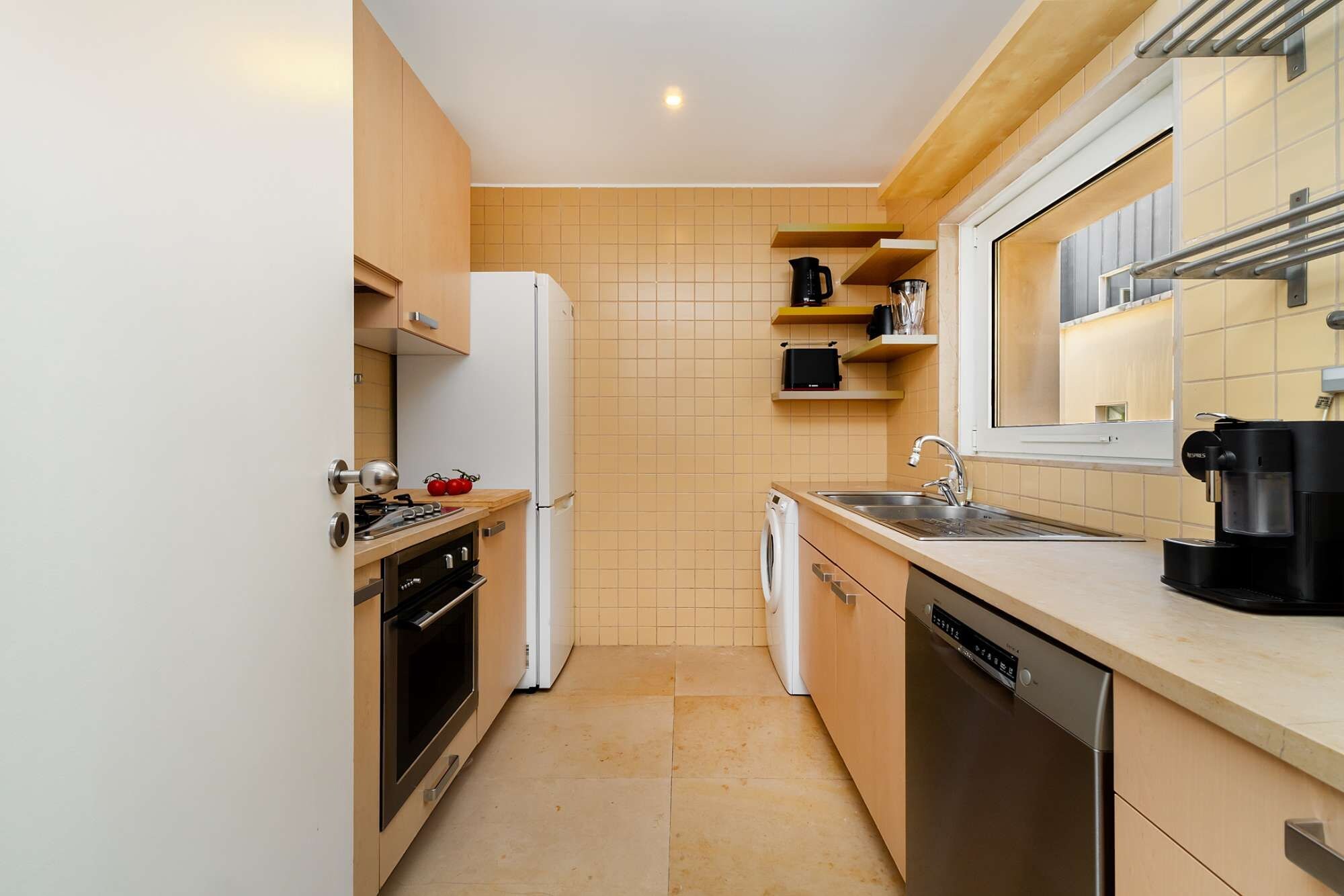 A compact kitchen with a refrigerator, oven, dishwasher, and a coffee machine.
