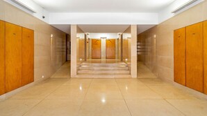 Ein Hotelgang mit Holfachschränken an beiden Seiten, einem gefliesten Boden und einer Treppe, die in eine höhere Ebene führt.