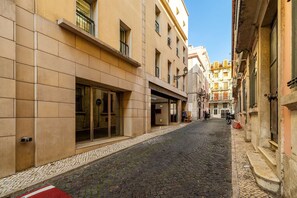 A narrow cobblestone street flanked by buildings with large windows and doors, suggesting a commercial area. - Experience the Spirit of Historic Lisbon (Lisbon)