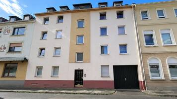 Ein mehrstöckiges Gebäude mit einer glatten Fassade, einem zentralen Eingang und einer schwarzen Garagentür.