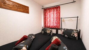 A room with a bed, a wooden wall art, a red curtain, and a black metal rack with hangers. - Cozy apartment in Boppard (Boppard)