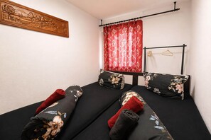 A room with a bed, a wooden wall art, a red curtain, and a black metal rack with hangers. - Cozy apartment in Boppard (Boppard)