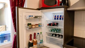 An open refrigerator stocked with various food items and beverages, including wine, beer, and canned drinks. - Cozy apartment in Boppard (Boppard)