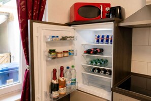 An open refrigerator stocked with various food items and beverages, including wine, beer, and canned drinks. - Cozy apartment in Boppard (Boppard)