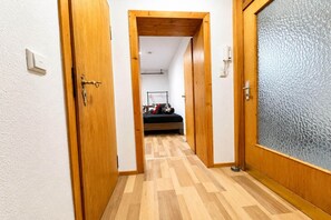 A hallway with wooden doors, a bed with a black mattress, and a hanging coat rack. - Cozy apartment in Boppard (Boppard)
