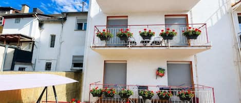 Un edificio de varios pisos con balcones, cada uno decorado con macetas de flores.