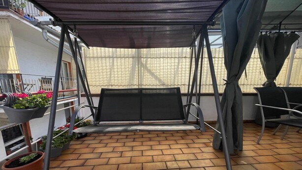 A covered patio area with a swing seat, potted plants, and a chair. - Cozy apartment in Boppard (Boppard)