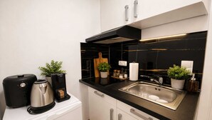 Una cuina moderna amb taulell negre, un vàter d'acer inoxidable i armaris blancs.