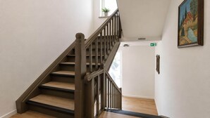 Una escala de fusta amb barana que condueix a una porta i un senyal d'emergència.