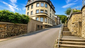 Une rue où, à l’angle, se trouve un immeuble portant l’inscription « Zum Steinberg ».