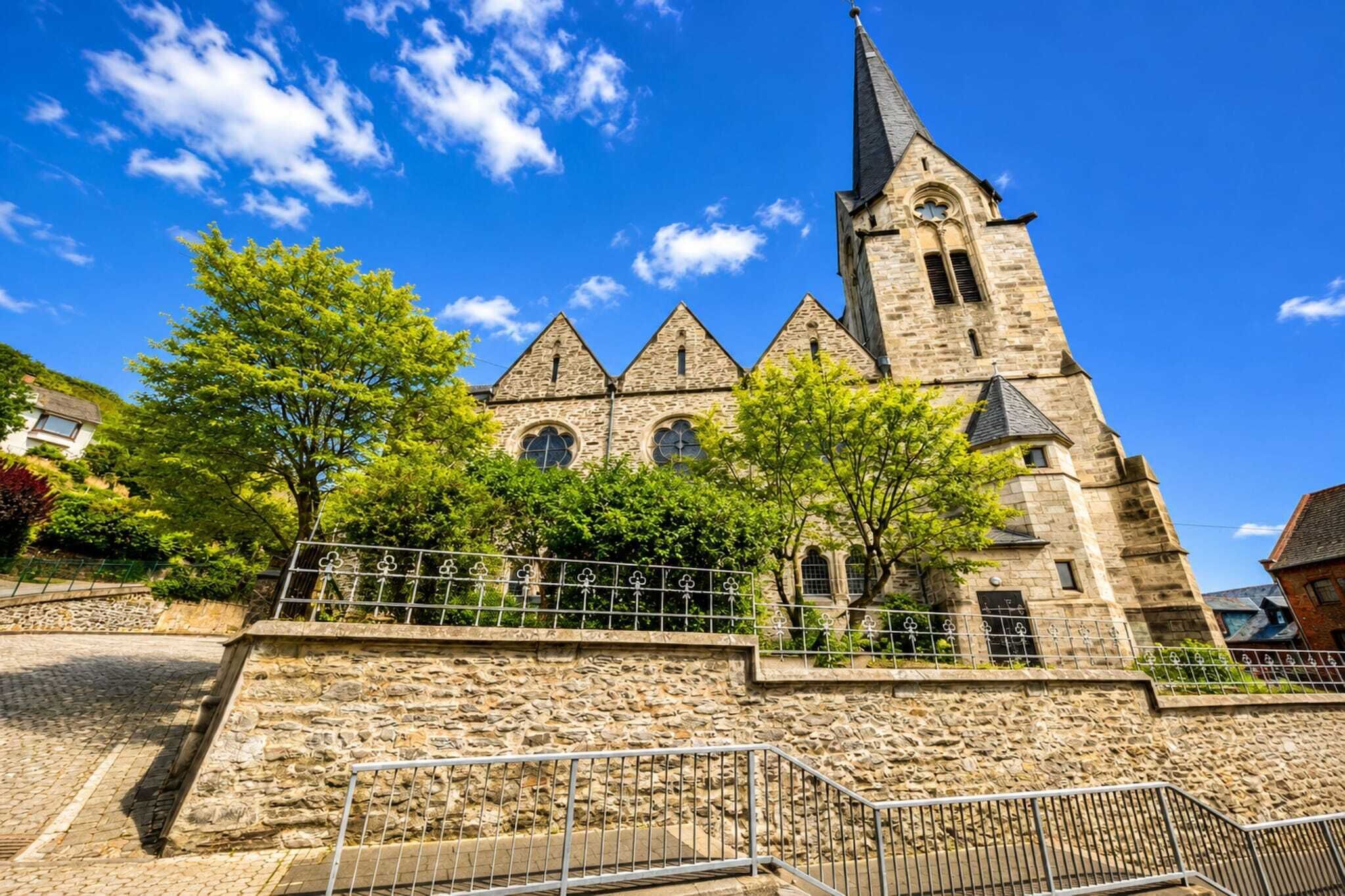 Une église historique en pierre, dotée d’un haut clocher et de fenêtres en arc.