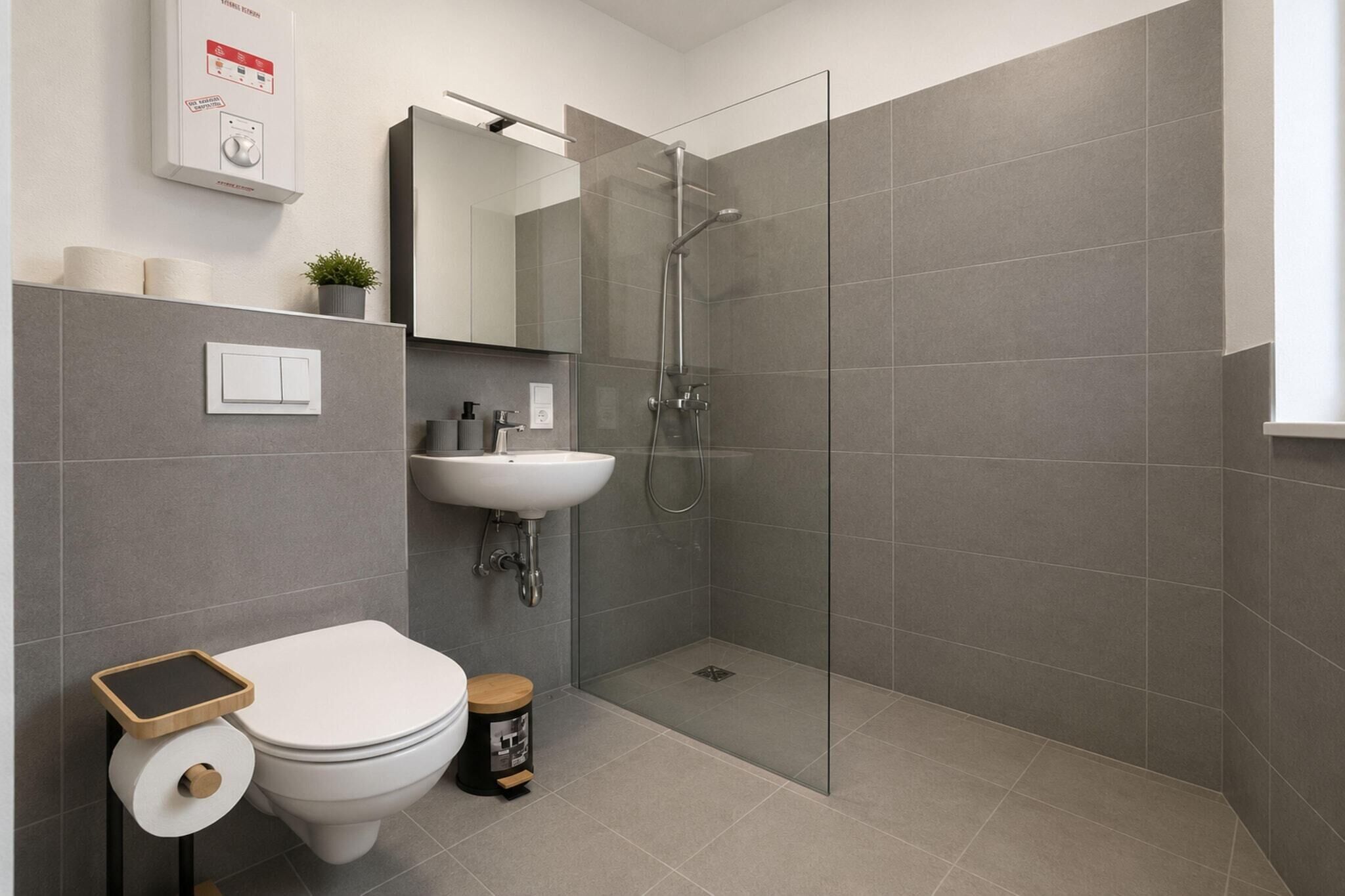 A modern bathroom with a toilet, sink, and glass-enclosed shower.