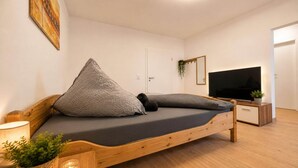 Un dormitorio moderno con una cama de madera, un televisor y una puerta.