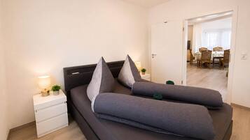 Ein modernes Schlafzimmer mit Bett, Nachttischen und Blick in den Essbereich.