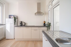 Eine moderne Küche mit eingebautem Ofen, einer Kaffeemaschine und einem Spülbecken aus Edelstahl.