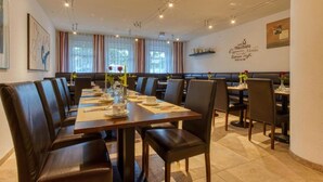 A restaurant with a long table set for dining, booths, and a wall with a menu.