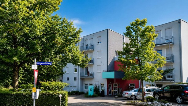 A multi-story residential building with a modern design, featuring balconies and a red facade. - Stuttgart Großbettlingen Hotel by Belvilla Comfort Room (Großbettlingen)