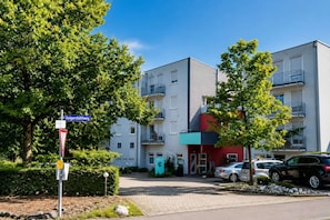 Um edifício residencial de vários andares com design moderno, apresentando varandas e fachada vermelha.