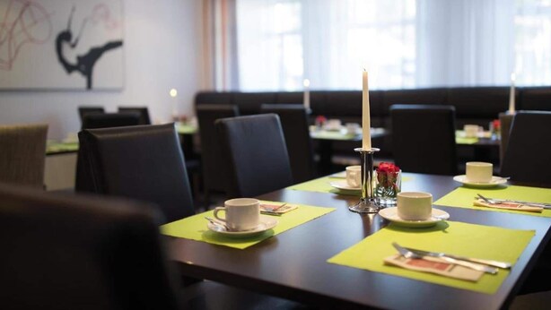 Un salón de conferencias con una larga mesa, sillas y un centro de mesa con velas.