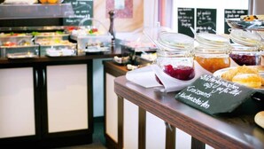Un'area buffet con diverse opzioni alimentari, tra cui barattoli di marmellata e dolci.