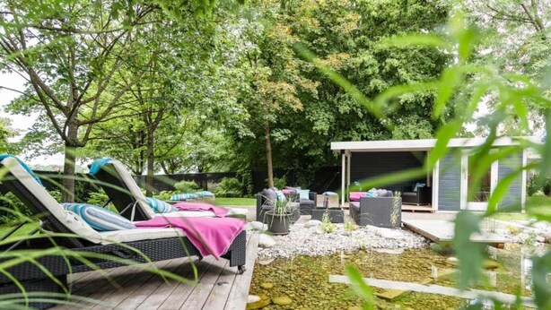 A deck with lounge chairs and a small pond, surrounded by trees and a covered seating area. - Stuttgart Großbettlingen Hotel by Belvilla Family Apartment (Großbettlingen)