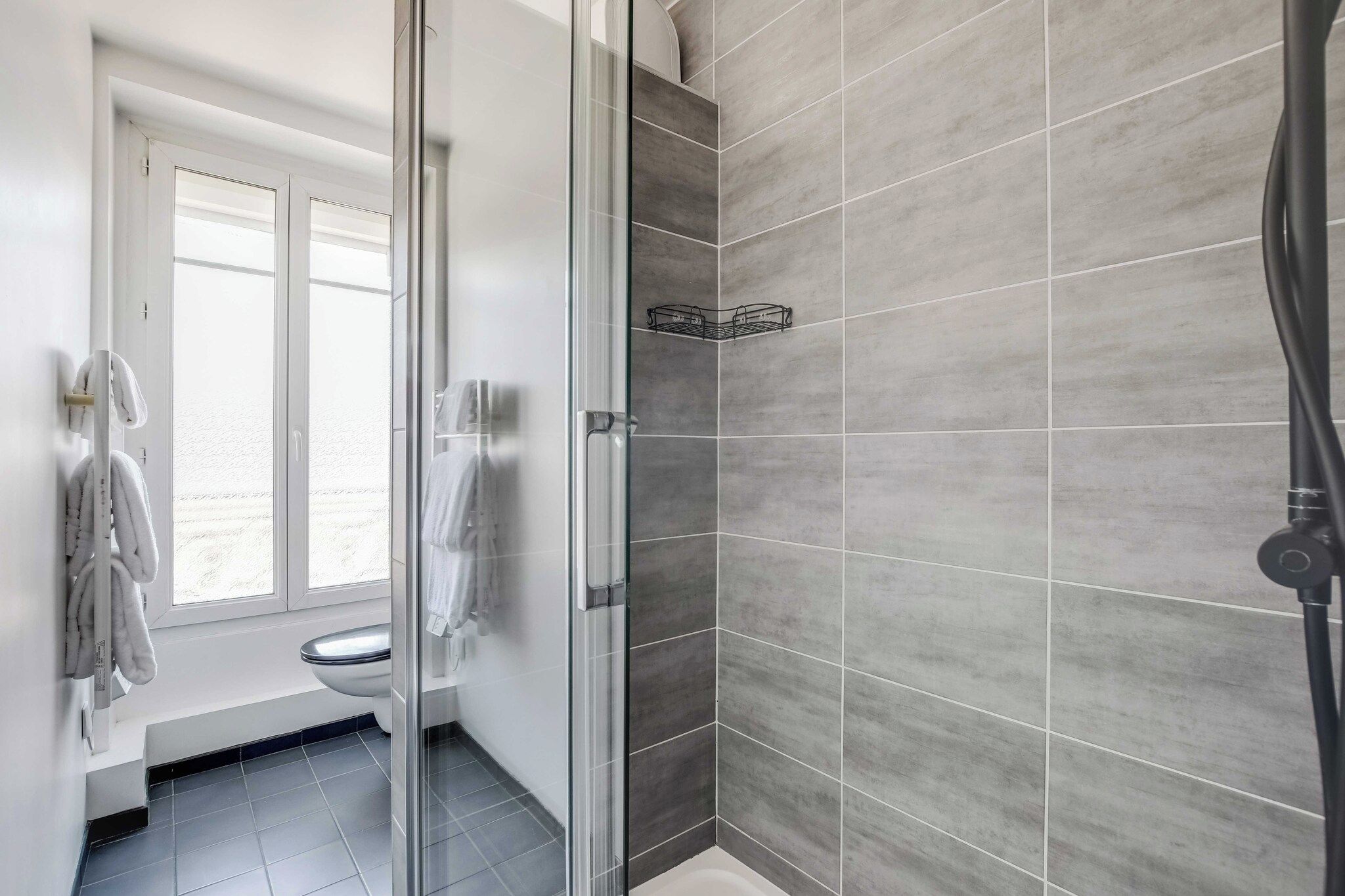 Ein modernes Badezimmer mit Duschkabine aus Glas, Toilette und Handtuchhalter.