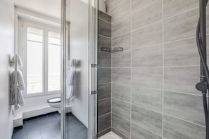 Ein modernes Badezimmer mit Duschkabine aus Glas, Toilette und Handtuchhalter.