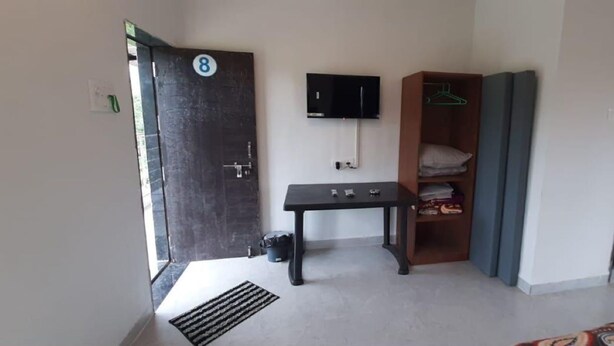 Una habitación con una puerta marcada con el número 8, una mesa negra, un armario de madera y un televisor instalado en la pared.