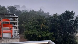 Vista de un balcón con barandilla de metal y una fila de sillas naranjas.