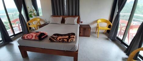 Habitación de hotel con una cama grande, dos sillones, una mesita y vistas al exterior.