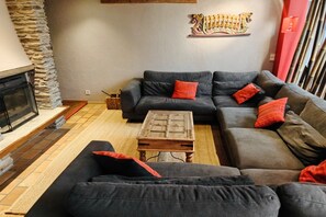Una sala de estar moderna con chimenea, sofás oscuros y una mesa de centro de madera.
