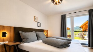 Hotelkamer met een groot bed, houten hoofdeinde, nachtlampjes, een klein tafeltje en uitzicht op het omliggende landschap.