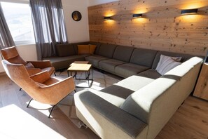 A modern living room with a sectional sofa, a chaise lounge, a coffee table, and a wall-mounted clock. - Ski-in/ski-out chalet with beautiful view (St. Lambrecht)