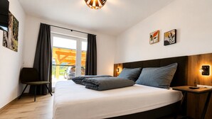 Een hotelkamer met een groot bed, een houten vloer, een stoel en uitzicht.