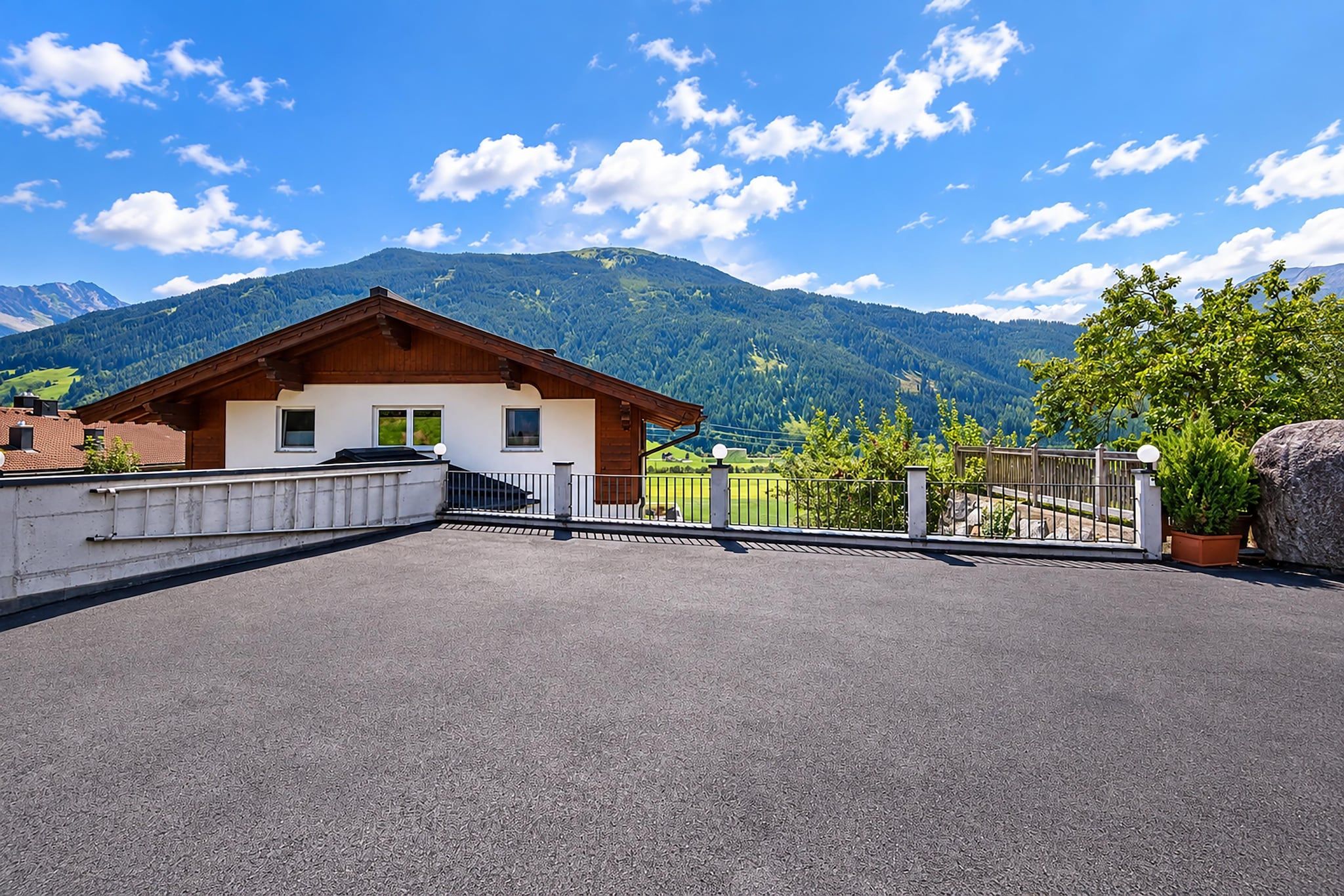 A chalet with a sloped roof, a balcony, and a view of a mountain range.