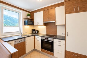 Eine moderne Küche mit Holzschränken, einer eingebauten Mikrowelle, einer Kaffeemaschine und einem Geschirrspüler.