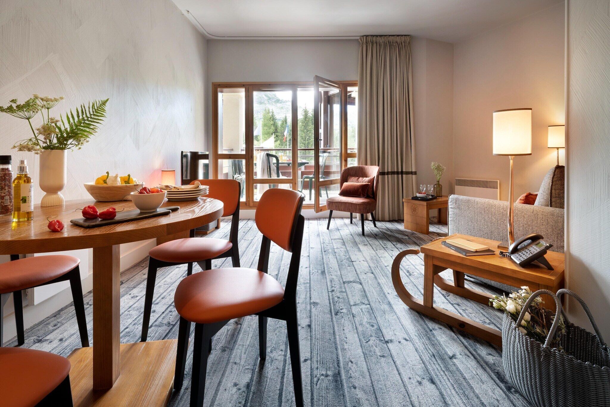 A hotel room with a dining area, a sofa, a telephone, and a view of the outdoors.