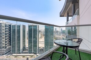 Ein Balkon mit Glastrennwand, einem kleinen runden Tisch und zwei Stühlen.