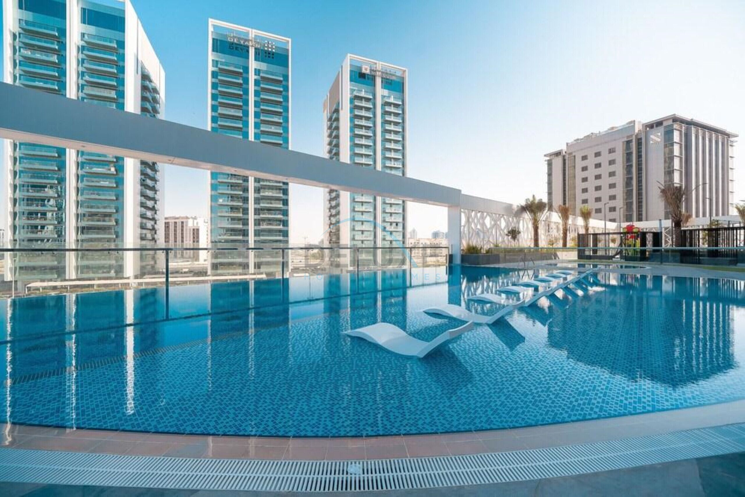 A swimming pool with clear blue water, surrounded by modern buildings with balconies.