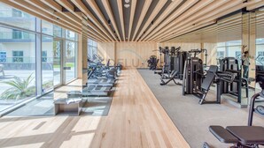 Un gimnasio con equipamiento de ejercicio, ventanas amplias y techo de madera.
