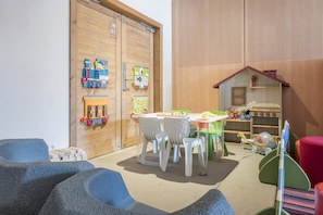 A children's playroom with a wooden door, a table with chairs, and various toys. - Luxury 10-Person Alpine Panoramic Suite (Flaine)