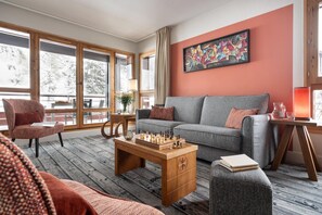 A cozy living room with a grey sofa, a wooden coffee table with chess, and large windows. - Picturesque Mountain Escape for 6 (Flaine)