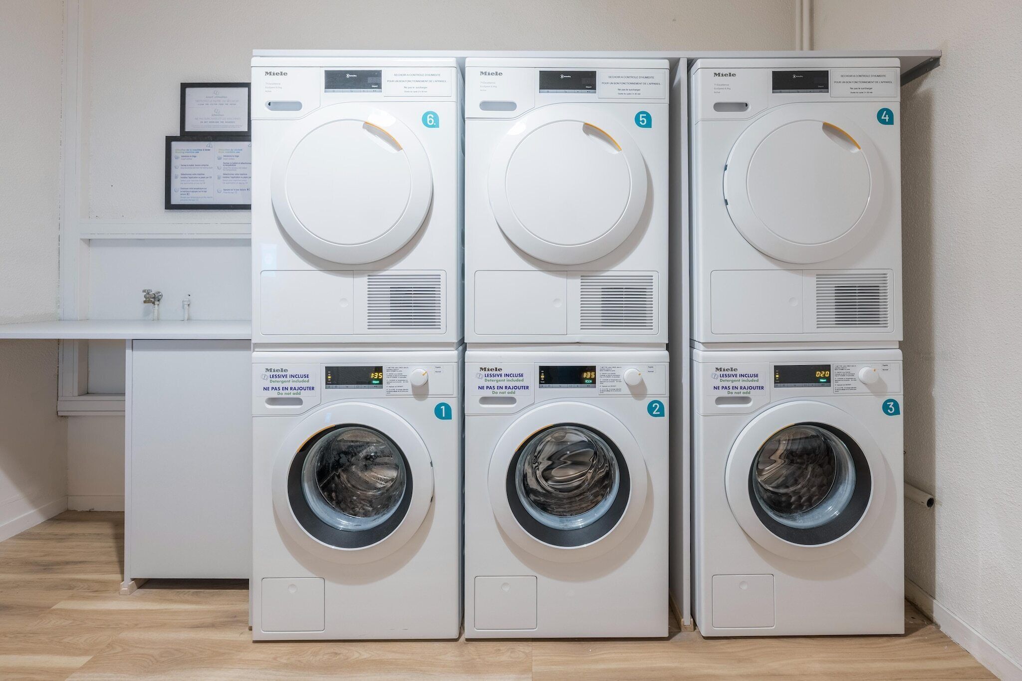 Four white front-loading washing machines stacked in two rows, each with a control panel and a digital display.