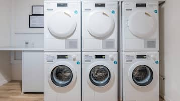 Four white front-loading washing machines stacked in two rows, each with a control panel and a digital display.