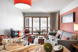 A modern living room with a sofa, a dining table, and a television. - Aesthetic 4-Person Alpine Sanctuary (Flaine)