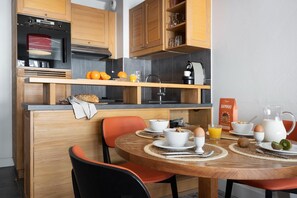 A modern kitchen with wooden cabinets, a built-in oven, and a breakfast setup with bowls, eggs, and a coffee machine. - Aesthetic 4-Person Alpine Sanctuary (Flaine)