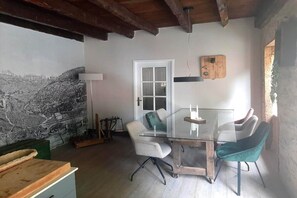 A dining area with a glass table and chairs, a white door, and a rustic wall. - Comfortable and authentic holiday home in Orgnac-sur-Vézère on the Vézère (Orgnac-sur-Vézère)