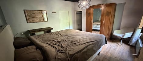 Un dormitorio con cama, banco de madera, lámpara colgante y armario.