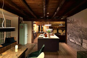 A rustic kitchen with wooden beams, a refrigerator, and a dining area with a table and chairs. - Comfortable and authentic holiday home in Orgnac-sur-Vézère on the Vézère (Orgnac-sur-Vézère)