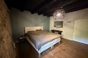 Un dormitorio con una cama, una mesita de noche, un espejo y una puerta.
